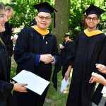 Graduates stand together talking.