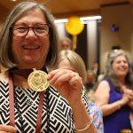 A woman holds up her medal